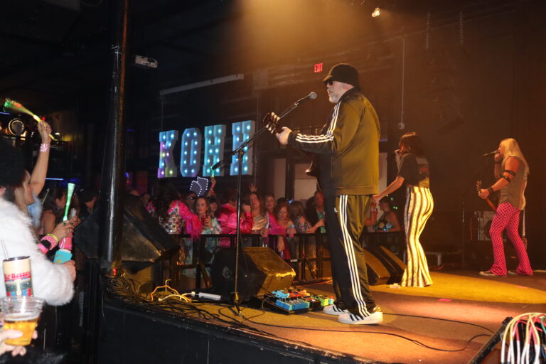 Fly By Radio performing on stage at the 2026 Krewe of Hip Huggers Ball in Pensacola, Florida.